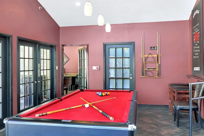 Chic game room featuring a striking red pool table, elegant French doors, and stylish seating area for ultimate relaxation and fun.