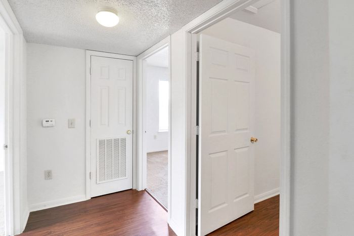 Bright, inviting hallway with hardwood floors and white doors leading to cozy living spaces.