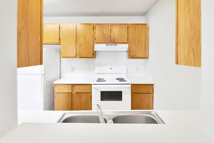 Bright and welcoming kitchen with modern white appliances and warm wooden cabinetry.