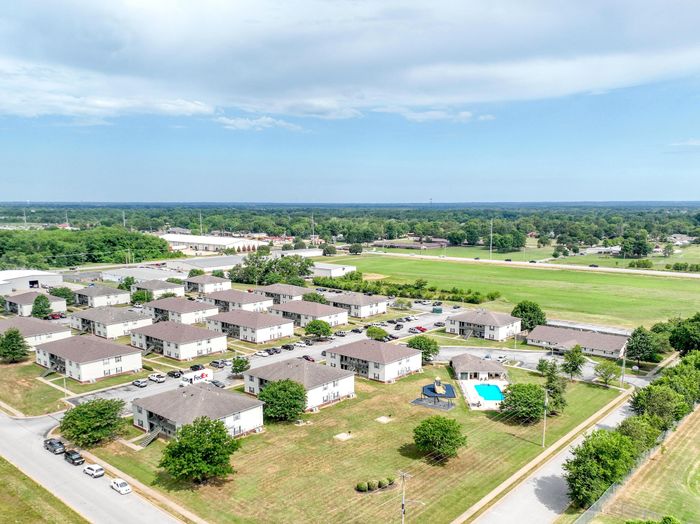 Charming residential community with multiple buildings, lush greenery, and inviting outdoor pool, offering a peaceful suburban lifestyle.