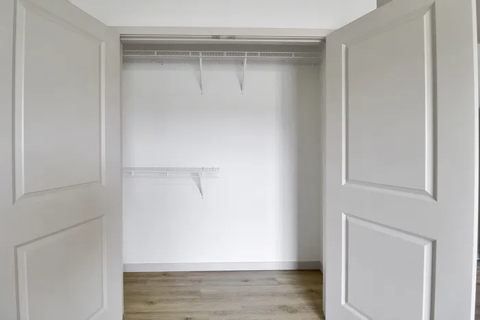 Spacious walk-in closet with sleek shelving and modern double doors, perfect for organized living.