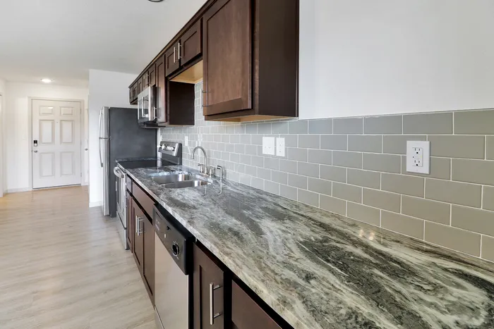 Modern kitchen with sleek granite countertops, stylish subway tile backsplash, and stainless steel appliances, creating a welcoming space for culinary creativity.