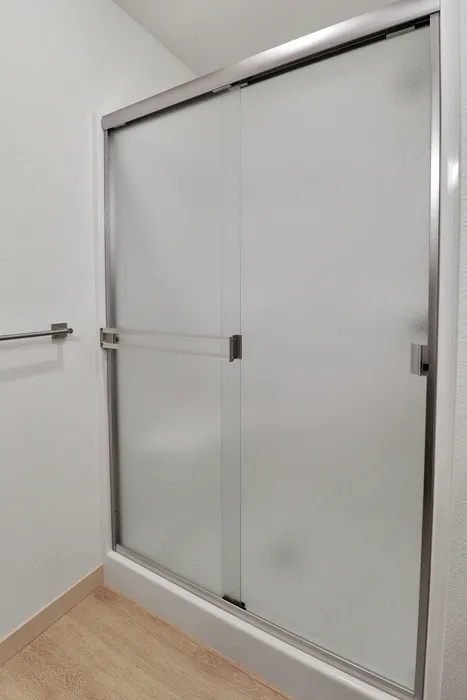 Sleek bathroom featuring elegant frosted glass sliding shower doors with modern metal accents.