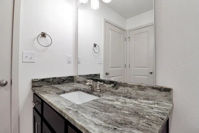 Elegant bathroom showcasing a sleek marble countertop with modern fixtures and ample mirror space.