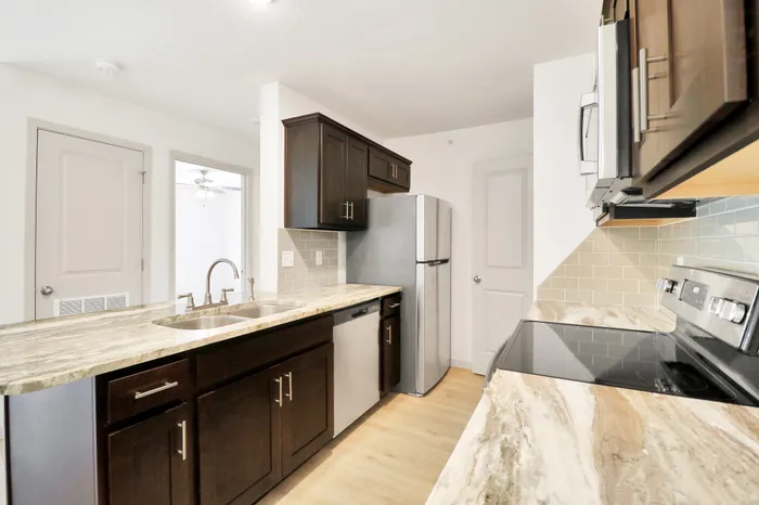 Modern kitchen with sleek stainless steel appliances, granite countertops, and elegant dark cabinetry, offering a stylish and functional space.