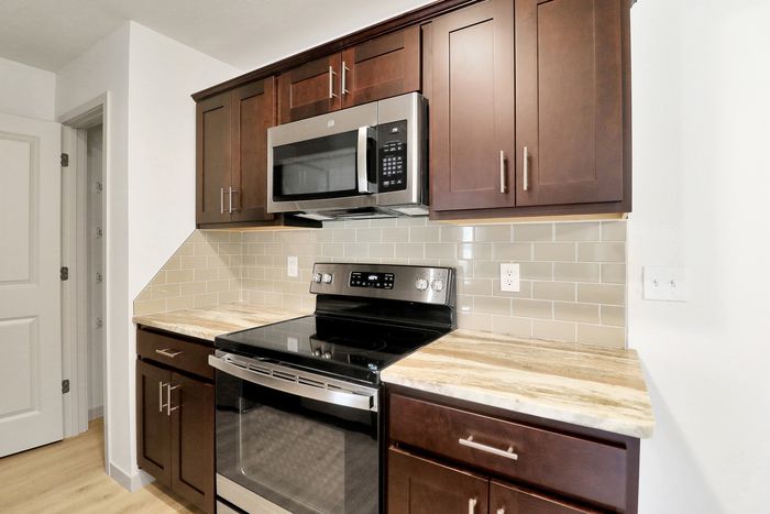 Modern kitchen with sleek stainless steel appliances, elegant dark wood cabinets, and a beautiful stone countertop.