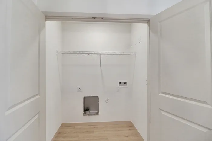 Spacious laundry room with sleek shelving and ample space for washer and dryer, offering modern convenience and style.