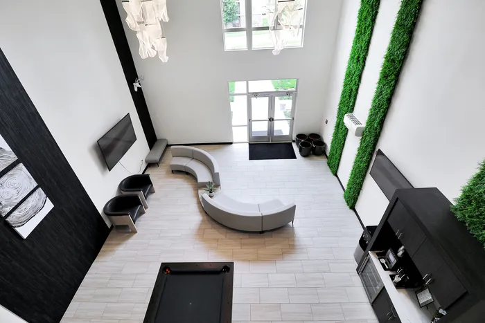 Modern lobby with elegant seating, high ceilings, and lush green accents, offering a welcoming and sophisticated atmosphere.