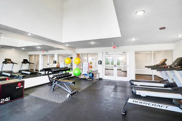 Modern apartment gym with state-of-the-art treadmills, weights, and vibrant exercise balls, offering a premium fitness experience.