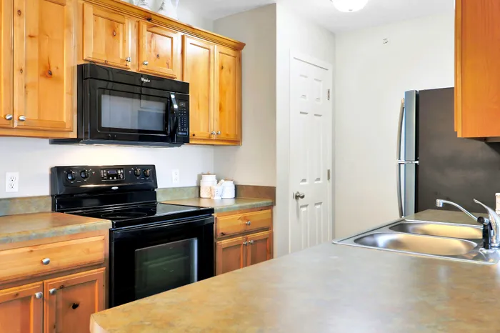 Charming kitchen featuring rustic wood cabinets, sleek black appliances, and a spacious countertop ideal for cooking.