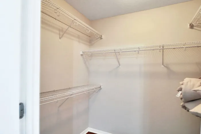 Spacious walk-in closet with clean shelving and ample storage space, perfect for organizing.