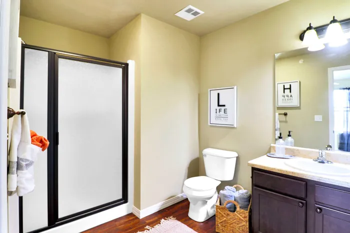 Elegant bathroom featuring a modern shower with glass doors, stylish vanity, and decorative wall art.