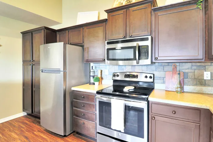 Modern kitchen featuring elegant dark wood cabinetry, sleek stainless steel appliances, and a warm, inviting atmosphere.
