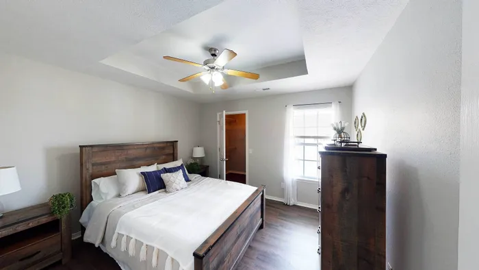Elegant bedroom with a rustic wooden bed frame, cozy linens, and a walk-in closet, complemented by natural light and modern decor.