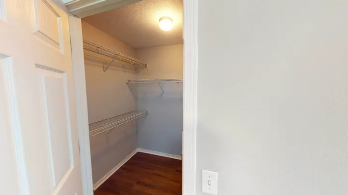 Spacious walk-in closet with ample shelving and warm lighting, perfect for organized living.
