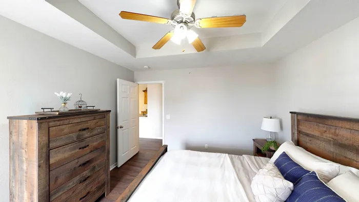 Bright and cozy bedroom with rustic wooden furniture, featuring a ceiling fan, modern design, and soft lighting for a welcoming atmosphere.