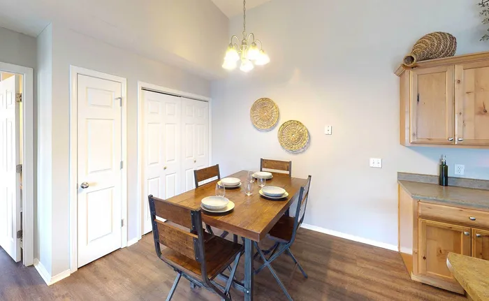 Charming dining area with rustic wooden table set for four, natural wood cabinetry, and stylish wall decor.