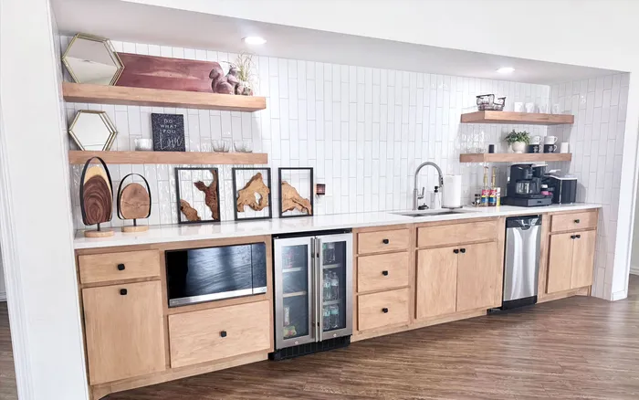 Chic kitchen area featuring stylish open shelving, modern wood cabinetry, sleek appliances, and a pristine tiled backsplash.