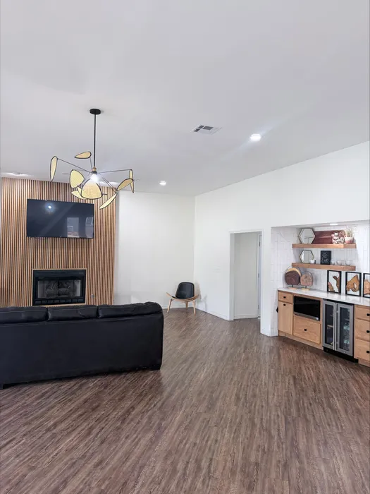 Contemporary living room with elegant lighting, modern fireplace, and open-concept kitchen in a stylish apartment.