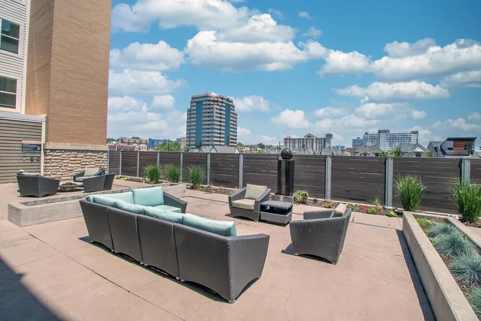 Chic urban rooftop lounge with modern wicker seating and skyline views, ideal for outdoor relaxation.