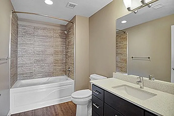 Elegant bathroom with modern fixtures, featuring a spacious bathtub, stylish vanity, and warm lighting.