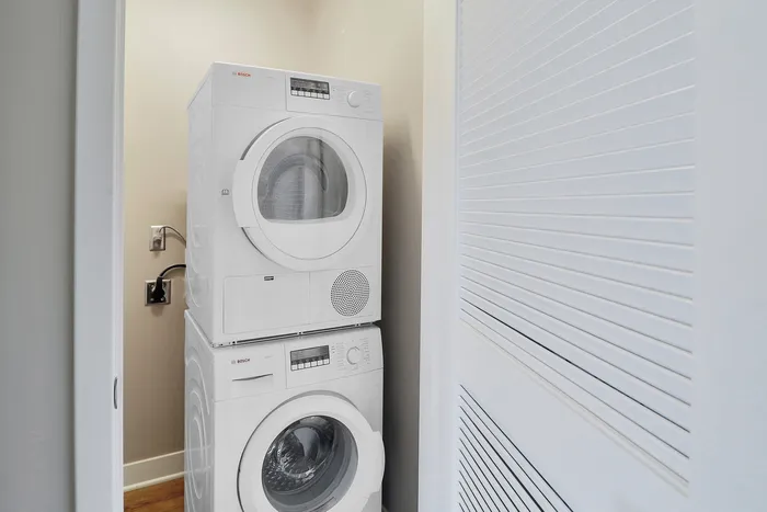 Contemporary laundry nook featuring sleek, stacked Bosch washer and dryer units in a compact space.