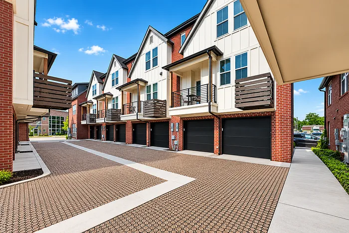 Contemporary townhouses with modern balconies and spacious garages set against a bright blue sky.