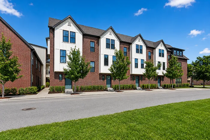 Charming brick townhouses with modern design and lush greenery, perfect for urban living.