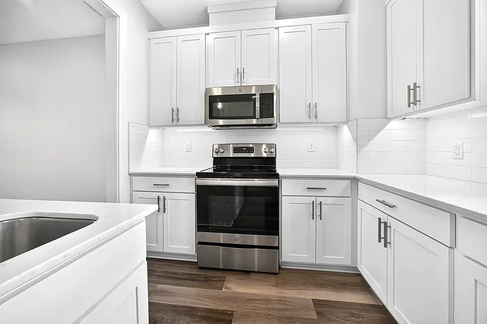 Modern kitchen with sleek stainless steel appliances, elegant white cabinetry, and chic tile backsplash.