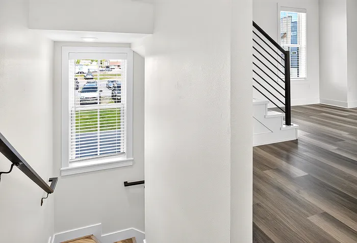 Bright modern apartment interior featuring sleek staircase design, elegant flooring, and natural light streaming through large windows.