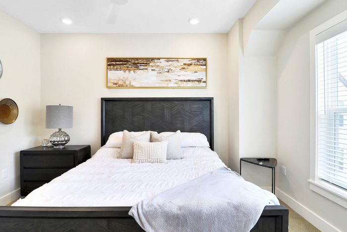 Bright, inviting bedroom featuring a stylish dark wood headboard, plush white bedding, and contemporary bedside decor.