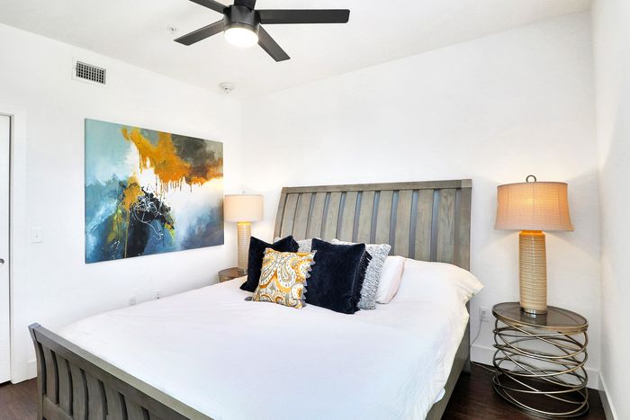 Bright, modern bedroom featuring a plush king-size bed with stylish pillows, abstract wall art, and elegant lighting.