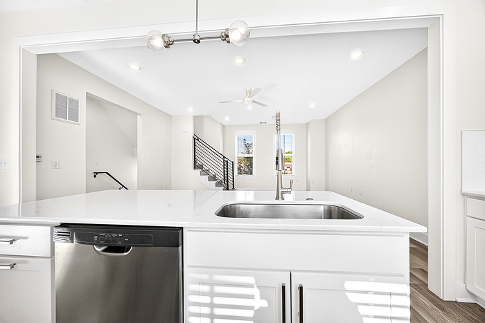 Bright and modern open-concept kitchen overlooking a spacious living area with large windows and sleek staircase.