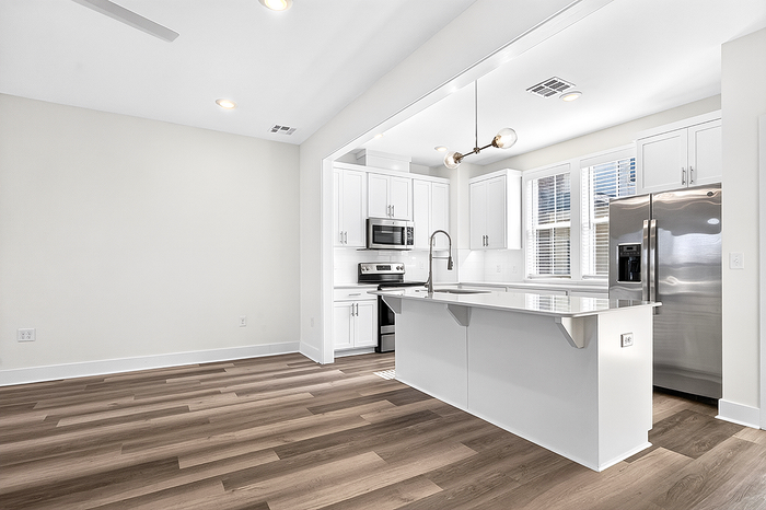 Bright, modern kitchen with sleek white cabinetry, stainless steel appliances, and a spacious breakfast bar. Open layout perfect for entertaining.