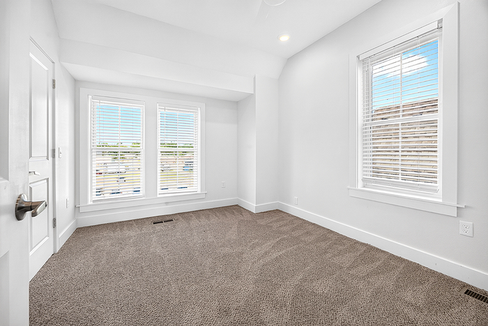 Bright and inviting room with plush carpeting and large windows, perfect for a cozy retreat or home office.