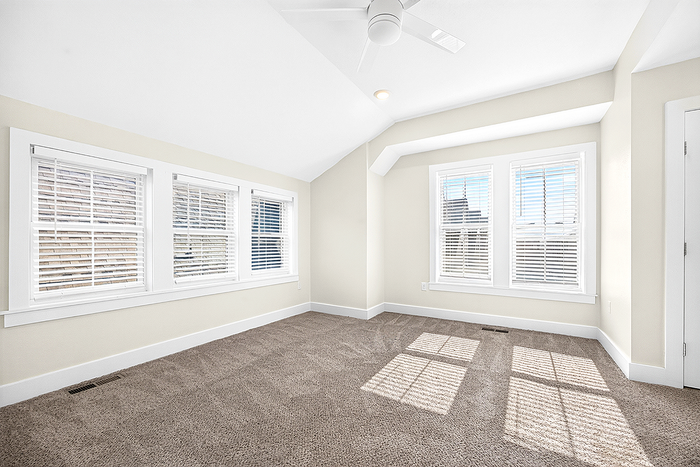 Bright and inviting room with plush carpet and ample natural light through large windows, perfect for a cozy retreat.