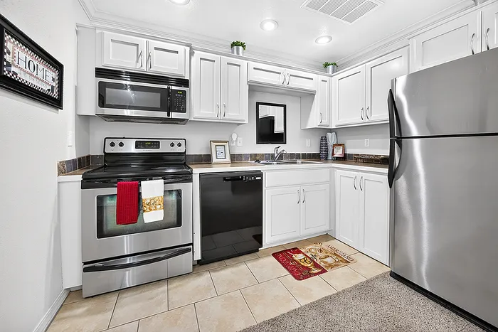 Chic kitchen with modern stainless steel appliances, pristine white cabinetry, and elegant tile flooring.