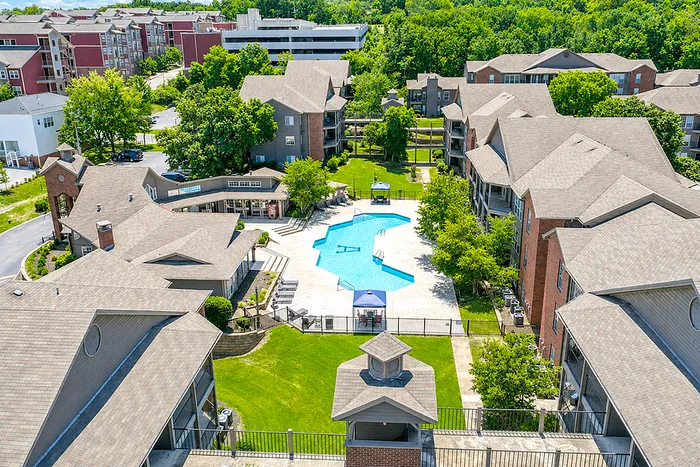 Charming apartment complex featuring a large swimming pool, lush greenery, and stylish architecture, perfect for modern living.