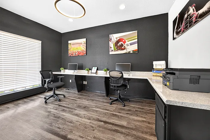 Modern home office with sleek black walls, ergonomic chairs, and dual computer setups, enhanced by bright natural light and sports-themed decor.