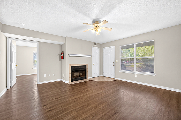 Inviting living room with elegant hardwood floors, classic fireplace, and abundant natural light from large windows.