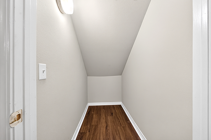 Charming cozy nook with elegant wooden flooring, perfect for a home office or storage space.
