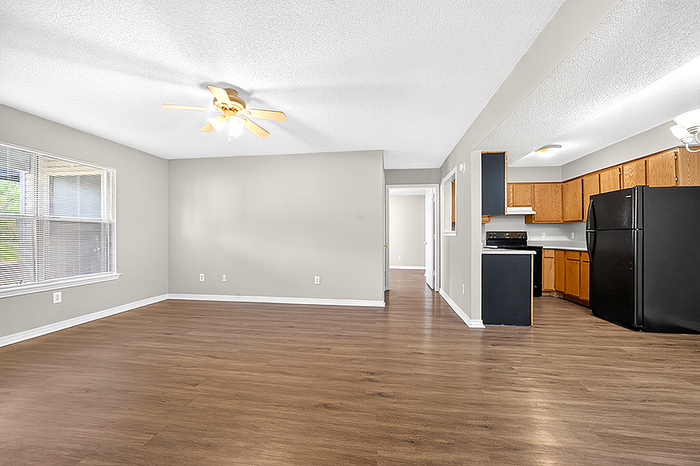 Bright open-concept living space with hardwood floors, modern kitchen, and large windows for natural light.