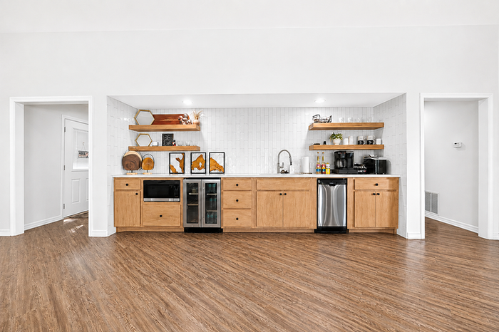 Modern kitchen with sleek wooden cabinets, open shelves, and stainless steel appliances accented by bright white walls and stylish d&eacute;cor.