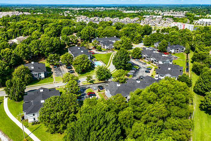 Charming residential complex nestled in lush greenery, offering serene living with multiple apartment buildings and a central pool area.
