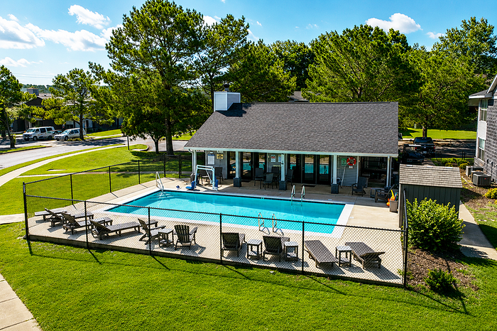 Inviting outdoor pool area with comfortable loungers surrounded by vibrant greenery and spacious sundeck.