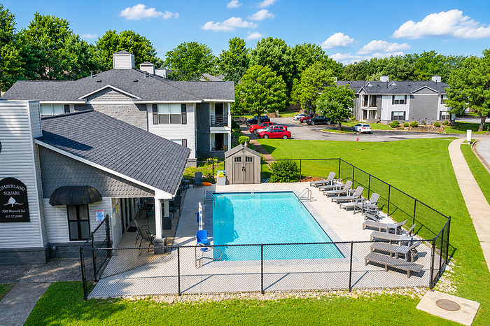 Inviting apartment community with a sparkling pool, lounge chairs, and lush greenery, perfect for relaxation and leisure.