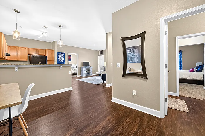 Elegant open-plan living area with warm wood flooring, contemporary lighting, and sleek kitchen design. Inviting spaces flow seamlessly into cozy bedrooms, perfect for modern living.