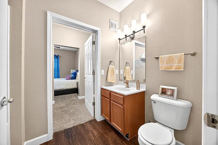 Elegant bathroom with warm lighting, stylish mirror, and cozy view into a chic bedroom.