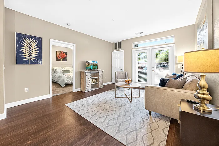 Bright and modern living room featuring elegant decor, natural light from large windows, and direct access to a cozy bedroom.