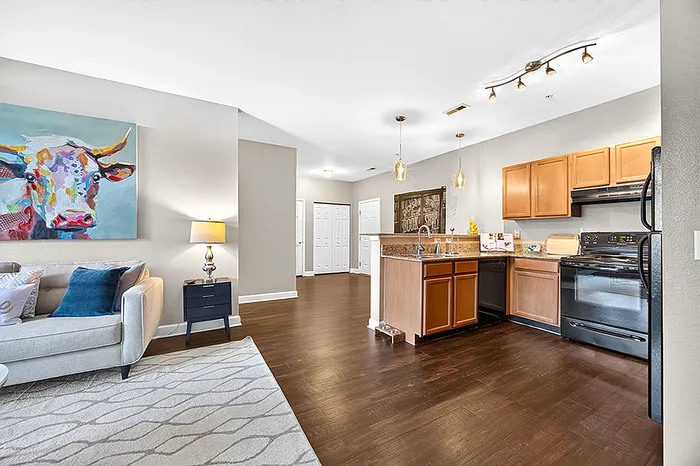 Chic open-concept living room and kitchen with modern décor, featuring a colorful painting and elegant hardwood floors.